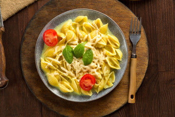 Pasta in cream sauce with cheese garnished with spinach with a fork on a wooden stand.