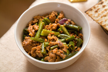 Green beans stewed in spices with meat and garlic on a laid table.