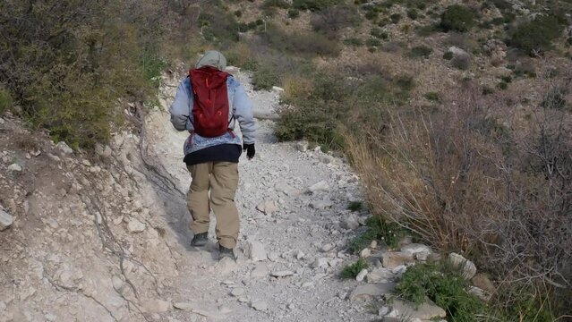 Hiker moves uphill as camera pans down switchback trail
