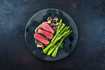 Gourmet barbecue dry aged angus beef steak with green asparagus and mushrooms in truffle mousse...