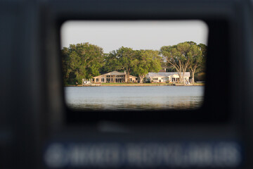 View shot through a Recycle Trash can by the water. With houses in the background across a bay On a sunny day in Florida. 