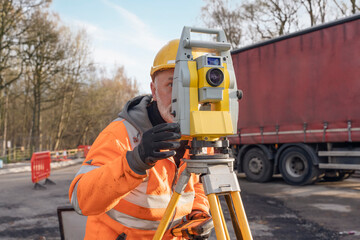 Site engineer operating his instrument during roadworks. Builder using total positioning station...