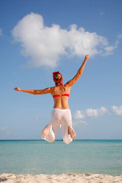 Woman in red and white jumping on the beach