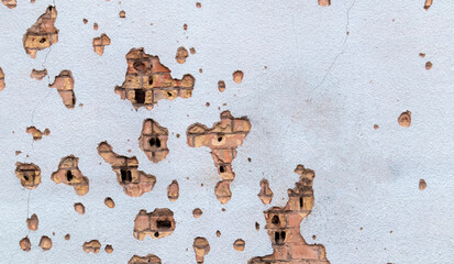 The wall of a building battered by rocket fragments in a war zone. Shelled wall. Facade of a...