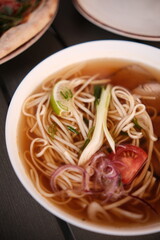 pho broth, Vietnamese soup in a deep plate with meat, wooden Chinese sticks and two quail eggs on a dark background