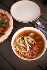pho broth, Vietnamese soup in a deep plate with meat, wooden Chinese sticks and two quail eggs on a dark background