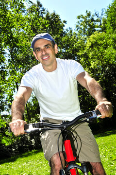 Happy middle aged man riding a bicycle in summer part