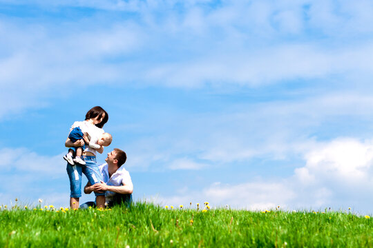 Happy mother, father and baby on the green hill