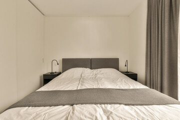 a bed in a room with curtains on either sides and the headboards up against each other one's wall