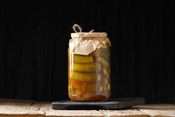 Pickled cucumbers in a jar on a dark background close-up, copy space.