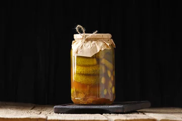 Fotobehang Pickled cucumbers in a jar on a dark background close-up, copy space. © Наталья Марная