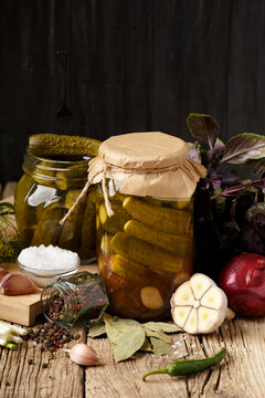 Pickled cucumbers in a jars on a dark wooden background.