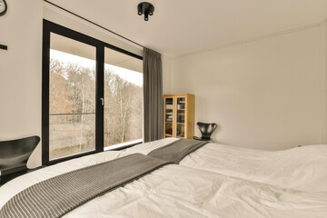 a bedroom with a bed, chair and large window looking out onto the trees in the photo is taken from outside