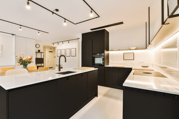 a modern kitchen with black cabinets and white countertops in the center of the image is an open -...