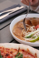 pho broth, Vietnamese soup in a deep plate with meat, wooden Chinese sticks and two quail eggs on a dark background