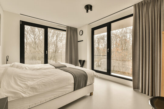 a bedroom with a bed and large windows looking out onto the trees that line the side of the room,