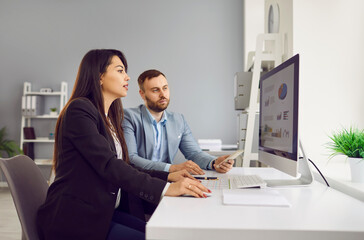 Side view portrait of business people discussing stats financial data on pc computer screen with diagram, charts sitting at the desk in office. Employees or staff analyzing company growth on meeting.