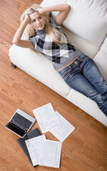 Obraz premium High angle view of a young woman frustrated while doing paperwork. Vertical shot.