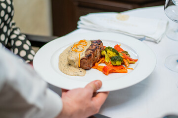 Waiter bringing food at the table and serving 