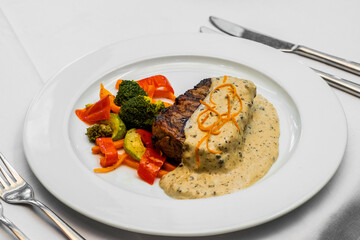 Delicious beef cutlet with grill vegetables on white plate. man cut and eat meat. men's hands holding knife and fork cutting steak