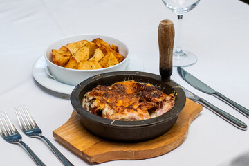 Cooked meat lasagna in black dish with baked potatoes in restaurant