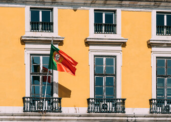 Portuguese flag on yellow facade reflecting on window