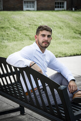 Fototapeta premium Young man sitting on a bench looking backward at the camera