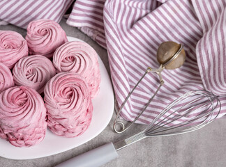 Fototapeta premium tasty delicious homemade zephyr pink marshmallows with blackberries taste.sweet dessert in box,on kitchen towel,gray tiles surface.whisk tea strainer accessories,sugar powder.pattern close up texture