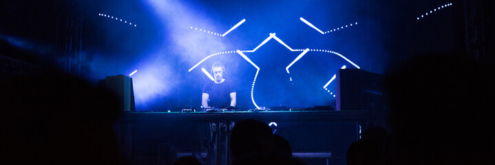 Dj playing techno music on the concert stage at summer night