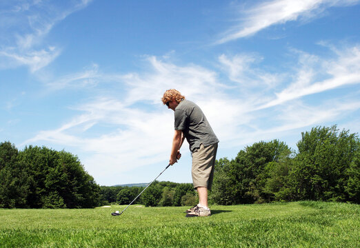 Man prepares to hit a golf ball on the course.