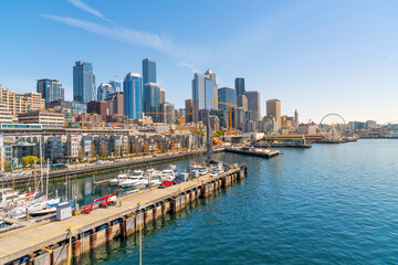 Panoramic view of the Seattle Waterfront along the Puget Sound with skyscrapers, the Pike Place Market district, the Great Wheel and Safeco Field in view from the harbor in Seattle Washington, USA. - obrazy, fototapety, plakaty