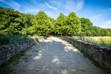 Fototapeta na wymiar Walking path over old stone bridge in park