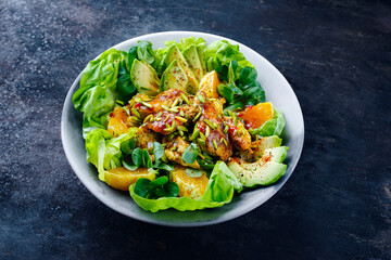 Traditioneller deutscher Eisberg und Feldsalat serviert mit Hähnchen, Avocado und Orangenscheiben mit pikanter süß saurer Currysauce serviert als Nahaufnahme auf einem Designteller mit Textfeld 