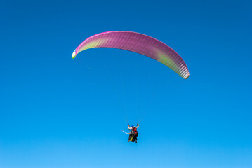 Two people (Instructor with student) flying with a paraglider above Sopelana beach near Bilbao...