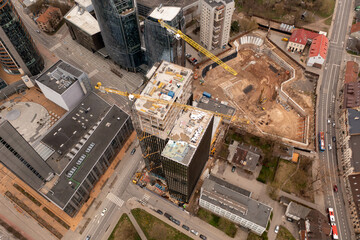 Drone photography of urban construction site of skyscraper complex in the middle of other structures during spring sunny day