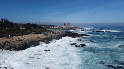 Vis&atilde;o a&eacute;rea da orla da praia chilena de Isla Negra captada do alto por um drone em um dia de sol.