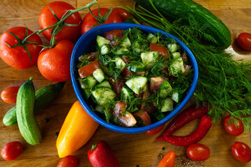 Fresh salad with cucumbers, tomatoes and dill in a blue bowl