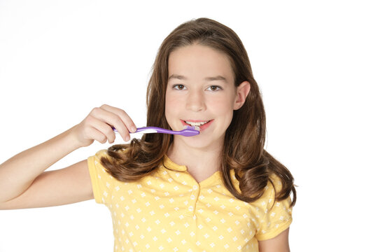 Cute Caucasion girl brushing her teeth isolated on a white background