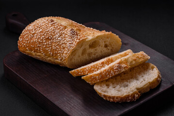 Crispy wheat flour baguette with sesame seeds on a wooden cutting board