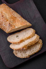 Crispy wheat flour baguette with sesame seeds on a wooden cutting board