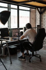 Concentrated young bearded male musician in headphones composing music on laptop during workday in...