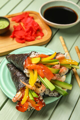Plate with tasty sushi cones, soy sauce, ginger and wasabi on color wooden background, closeup