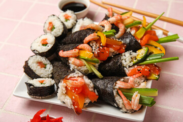 Plate with tasty sushi cones and rolls on color tile background, closeup