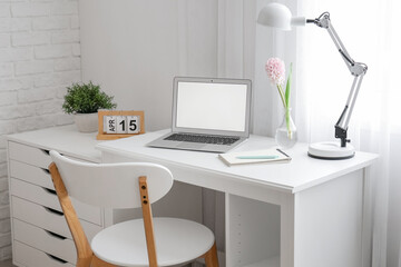 Comfortable workplace with modern laptop and beautiful hyacinth flowers near window