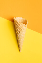 Empty wafer cone. Sweet ice cream cornet on colorful background. Top view.