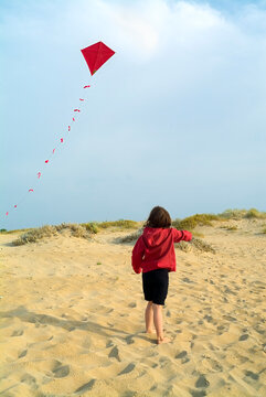 girl on beach and a red kite
