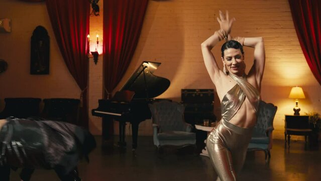 Beautiful slim fit asian woman dancing in classic theater interior. Glamorous couple making acrobatic twine split move. Asian professional dancer performing funk style moves dance in pair with male 4K