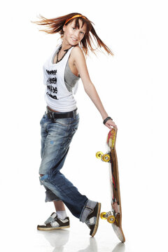 Portrait of smiling girl standing with skateboard on white background