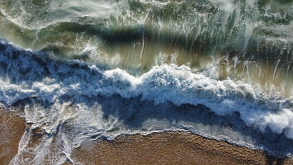 Fototapeta na wymiar Ondas na praia de Algarrobo no Chile captada do alto por um drone em um dia de sol de 2022. 