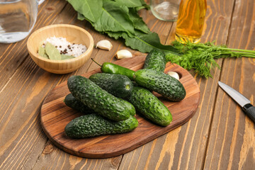 Board with fresh cucumbers for preservation on wooden background